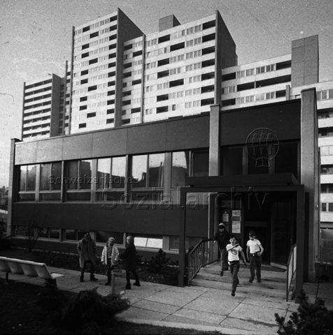 "Freizeitanlagen, Gemeinschaftszentren: Lochergut, Zürich" - Kinder beim Verlassen vom und beim Spielen vor dem Gebäude, im Hintergrund Wohnblöcke; um 1970