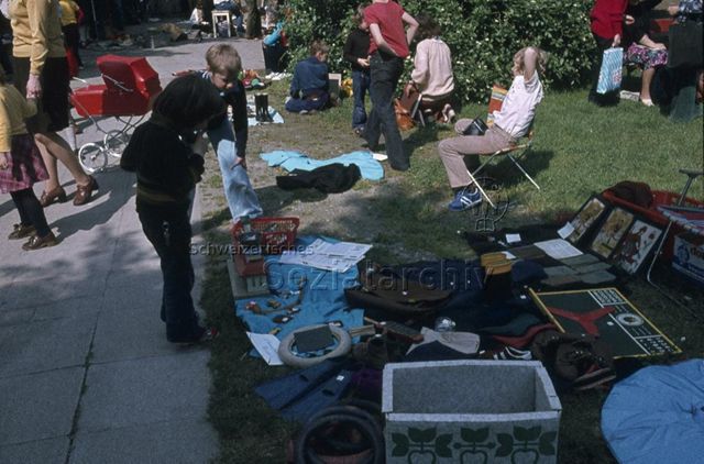 "Freizeitanlagen, Gemeinschaftszentren: Kinderflohmarkt Wipkingen, Zürich" - Kinder haben ihre Verkaufsware auf Tüchern auf dem Rasen ausgebreitet, um 1975