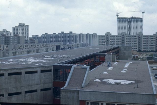 "Europäische Länder: Gropiusstadt, Berlin" - Blick von oben herab auf das Flachdach vermutlich eines Schulhauses, im Hintergrund sieht man ein grosses Quartier mit Wohnblöcken; um 1970