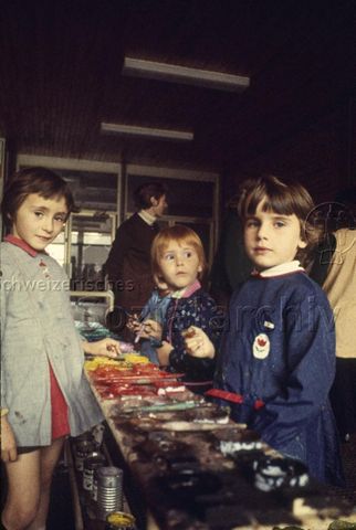 "Europäische Länder: Centre éducatif et culturel, Verres France" - Drei Mädchen stehen mit Pinseln in den Händen bei den Töpfchen mit Malfarben; um 1970