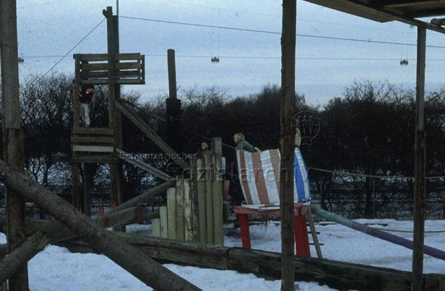 "Europäische Länder: Kopenhagen, Dänemark" - Spielplatz mit Holztürmen und -Brücken, zwei jungen sitzen in einem farbig bemalten Holzfass; um 1970