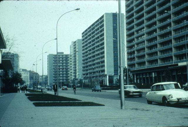 "Europäische Länder: Häuserblock ohne Spielgelände" - Von Wohnblöcken gesäumte Strasse, Gehsteig mit kleinen, begrünten Flächen; um 1970