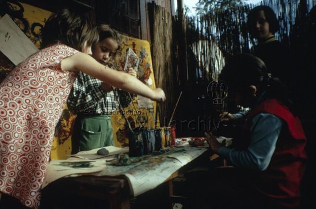 "Zeichnen und Malen: Robinsonspielplatz Volta, Basel" - Vier Kinder beim Bemalen von Steinen; um 1970