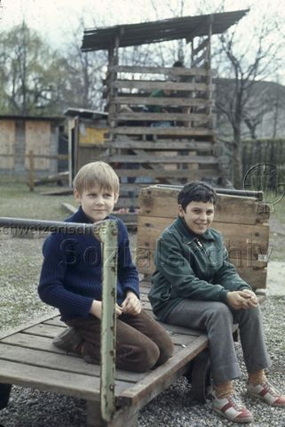 "Alter Postwagen auf Robinsonspielplatz Volta, Basel" - Zwei Jungen auf dem Wagen; um 1975