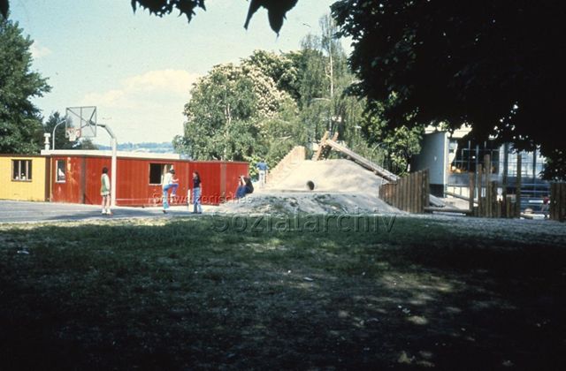 "Robinsonspielplatz 'Le Lignon', Genf" - Ansicht der Anlage, Kinder Jugendliche spielen Gummitwist; um 1975
