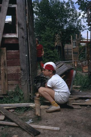 "Robinsonspielplatz Bachgraben, Basel" - Junge beim Abreissen einer Hütte; um 1975