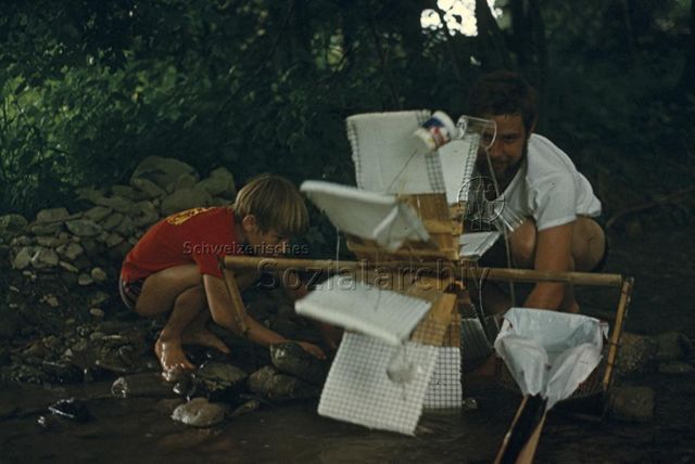 "Wasserrad" - Mann und Kind testen das selbstgebaute Wasserrad; um 1975