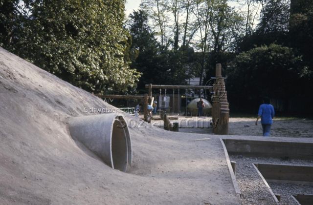"Robinsonspielplatz 'Le Lignon', Genf" - spielende Kinder, Kriechröhre, Schaukel; um 1975