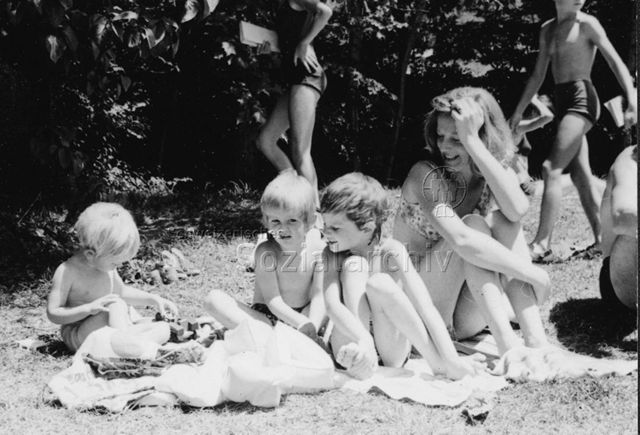 Bosco della Bella, Feriendorf für kinderreiche Familien - Mutter und drei Kinder sitzen auf Wiese, kleinstes Kind spielt; um 1975