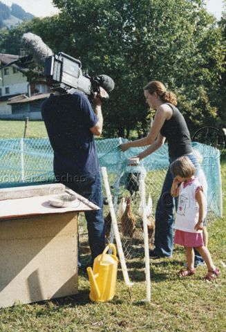PraktikantInnenhilfe: Einsätze - Praktikantin füttert die Hühner und wird von Kameramann gefilmt; 2000