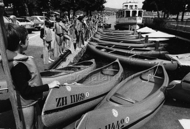 "Ferienpass, GZ Wollishofen", Zürich - Kinder mit Schwimmwesten und Rudern stehen vor Ruderbooten"; 1979