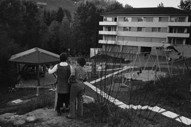 "Freizeitanlagen Schweiz", Siedlungsspielplatz Lichtensteig - Ansicht des Spielplatzes, zwei Kinder vor der Rutschbahn; 1970