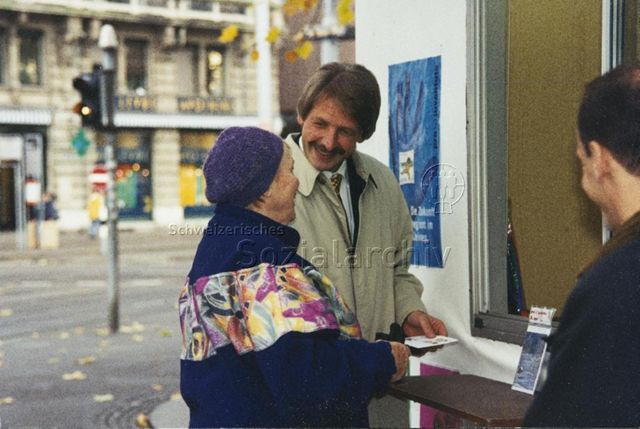 "Markenverkauf am Bellevue mit Zürcher Stadtpräsident Josef Estermann" - Herr Estermann im Gespräch mit einer Frau; 1997