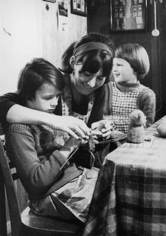 "Praktikantinnenhilfe" - Praktikantin und zwei Kinder beim Stricken; um 1965