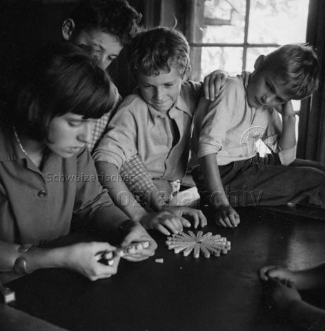 Praktikantinnenhilfe - Praktikantin und Kinder beim Basteln mit Wäscheklammern; um 1965