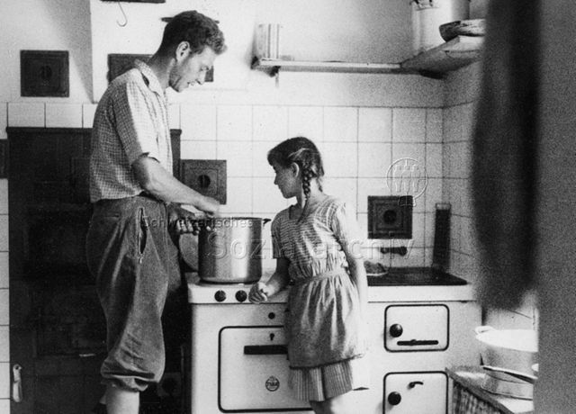 PraktikantInnenhilfe - Praktikant beim Kochen, Mädchen blickt in den Topf; um 1965