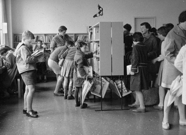 "Bibliothekfiliale Oerlikon, Abteilung für Kinder" - Kinder und Jugendliche beim Stöbern und Lesen; um 1965