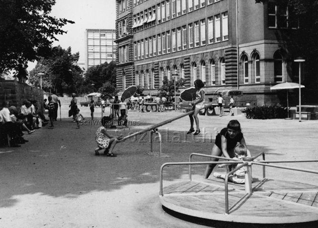 "Spielstrasse Durlacher Tor, Städt. Gartenbauamt Karlsruhe" - spielende Kinder auf Wippe und Drehkarussell; um 1970