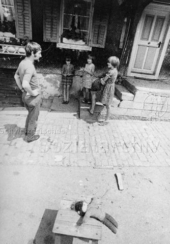 "Aktion 7, Dorflager Marbach" [Kanton Luzern oder St. Gallen] - Mann und drei Mädchen vor einem Haus; 1971