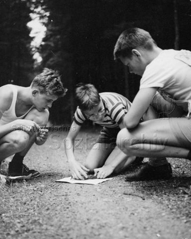 "Freizeitbeschäftigung aussen" - Drei Jungen beim Orientierungslauf finden mit Hilfe des Kompasses den richtigen Weg; um 1960