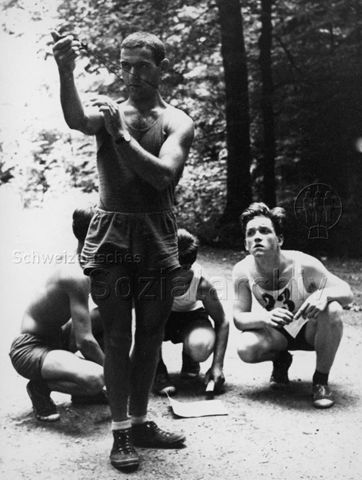 "Freizeitbeschäftigung aussen" - Drei Jungen und ein Mann beim Orientierungslauf suchen mit Hilfe eines Kompasses nach dem richtigen Weg; um 1960
