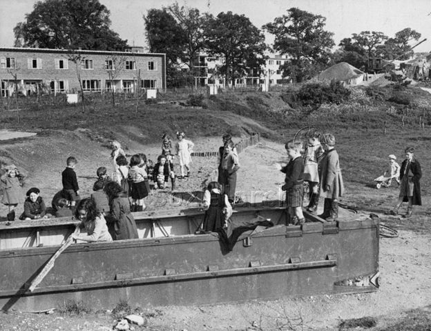"Harlow Development Corporation, Childrens' playgroud, Glebelands" - spielende Kinder, im Hintergrund Wohnhäuser; um 1955
