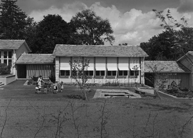 "3 Kindergärten, Burgfelderstrasse, Basel, Teilansicht, Arch. Hochbauamt" - Kinder und Kindergärtnerin beim Spielen auf der Wiese; um 1960