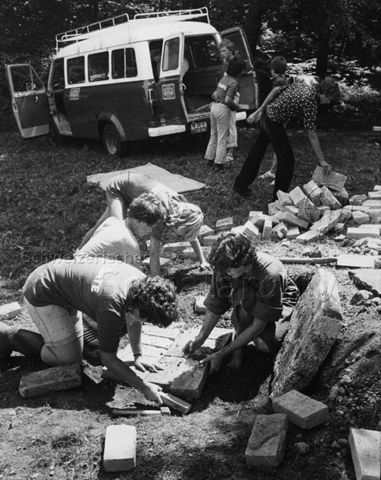 "Abenteuerlager Oberstammheim" - Vorne sind Jugendliche beim Verlegen von Steinen, hinten wird ein Bus entladen; um 1980