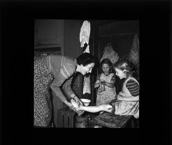 Diaserie "Reserve" und "alte Dias"; eine Frau am Waschen eines Beines von einem Mädchen mit einem Waschlappen; im Hintergrund ein weiteres Mädchen am Waschen seiner Hände mit einem Waschlappen; um 1950
