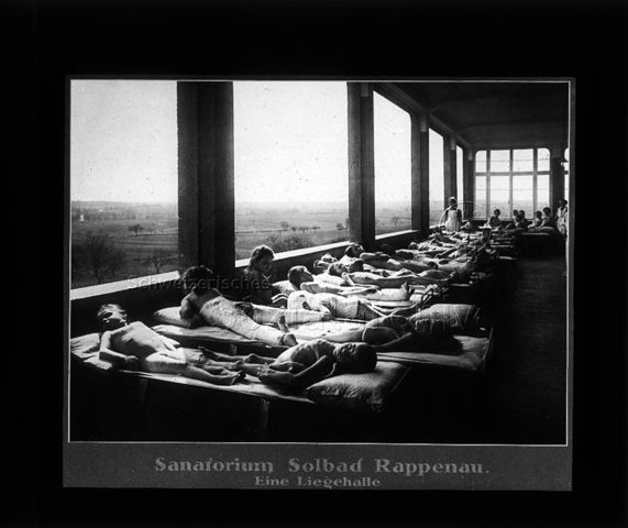 Diaserie zum Thema Tuberkulose im Kindesalter; "Sanatorium Solbad Rappenau. Eine Liegehalle" - Kinder nackt und mit Verbänden auf Betten in einer Halle mit grossen Fenstern liegend; Deutsches Hygiene-Museum; um 1930