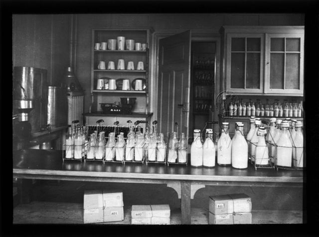 Diaserie zum Thema Säuglingspflege, Krippen; Milchflaschen in Flaschenträgern auf Tisch stehend; um 1930