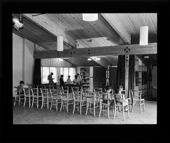 Diaserie zu Spielplätzen in Zürich; Robinsonspielplatz Wipkingen; "Klubraum + Bibliothek" - Jungen sitzen auf Stühlen; im Hintergrund Mädchen bei der Ausleihe von Büchern; um 1960