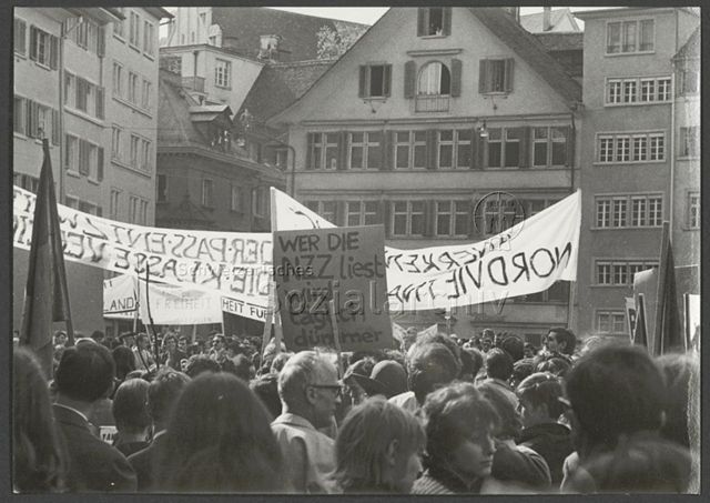 Kundgebung auf dem Münsterhof, Transparent "Wer die NZZ liest wird täglich dümmer", 1. Mai, Zürich, 1968