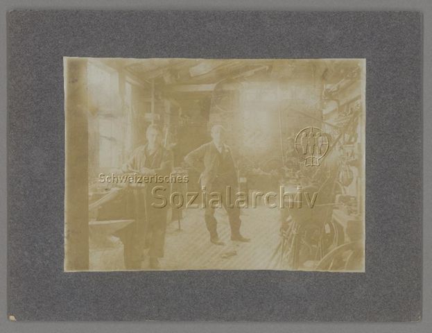 Arbeiter, Mann im Sakko in mechanischer Fahrradwerkstätte, Plakat an Wand "Neckarsulmer Fahrradwerke A.G.", Yverdon (?), um 1910