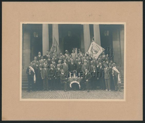Gruppenporträt des Grütli-Männerchors Zürich mit Männern in Anzügen, Pokalen und Fahnen "Grütli-Männerchor Zürich [...]", 1928