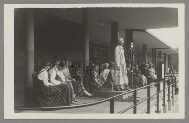 Lida Gustava Heymann auf Podest und mit Mikrophon bei Rede im Rahmen des Kongresses der Internationalen Frauenliga für Frieden und Freiheit (IFFF/WILPF) in Prag, 1929