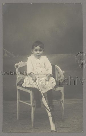 Atelieraufnahme von Kind auf Stuhl mit Gewehr vor sich, wahrscheinlich Provinz Girona, Spanien, datiert: 10.01.1918 (?)