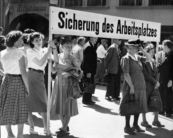 "Sicherung des Arbeitsplatzes " (Transparent einer Gruppe der Basler Bandweberinnen im Demonstrationszug auf dem Marsch nach Bern), 15. Juni 1952