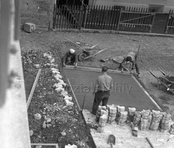Tiefbauarbeiter beim Pflästern eines Wegs, um 1960